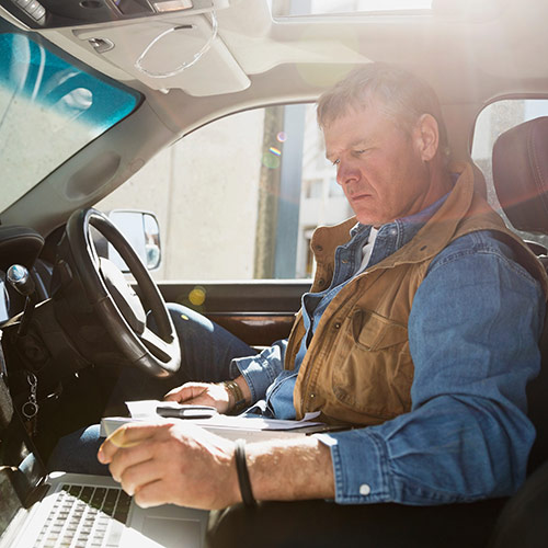 Contractor in Car Looking at Laptop